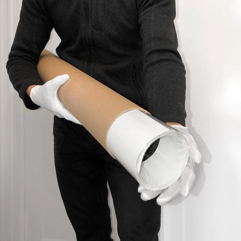 Dressed in black and wearing white gloves, a person holds the "Georgia Strait South No. 1" by The Silent Sea, a large brown cardboard tube with white ends, possibly preparing for an exclusive exhibition photograph in the Pacific Northwest.